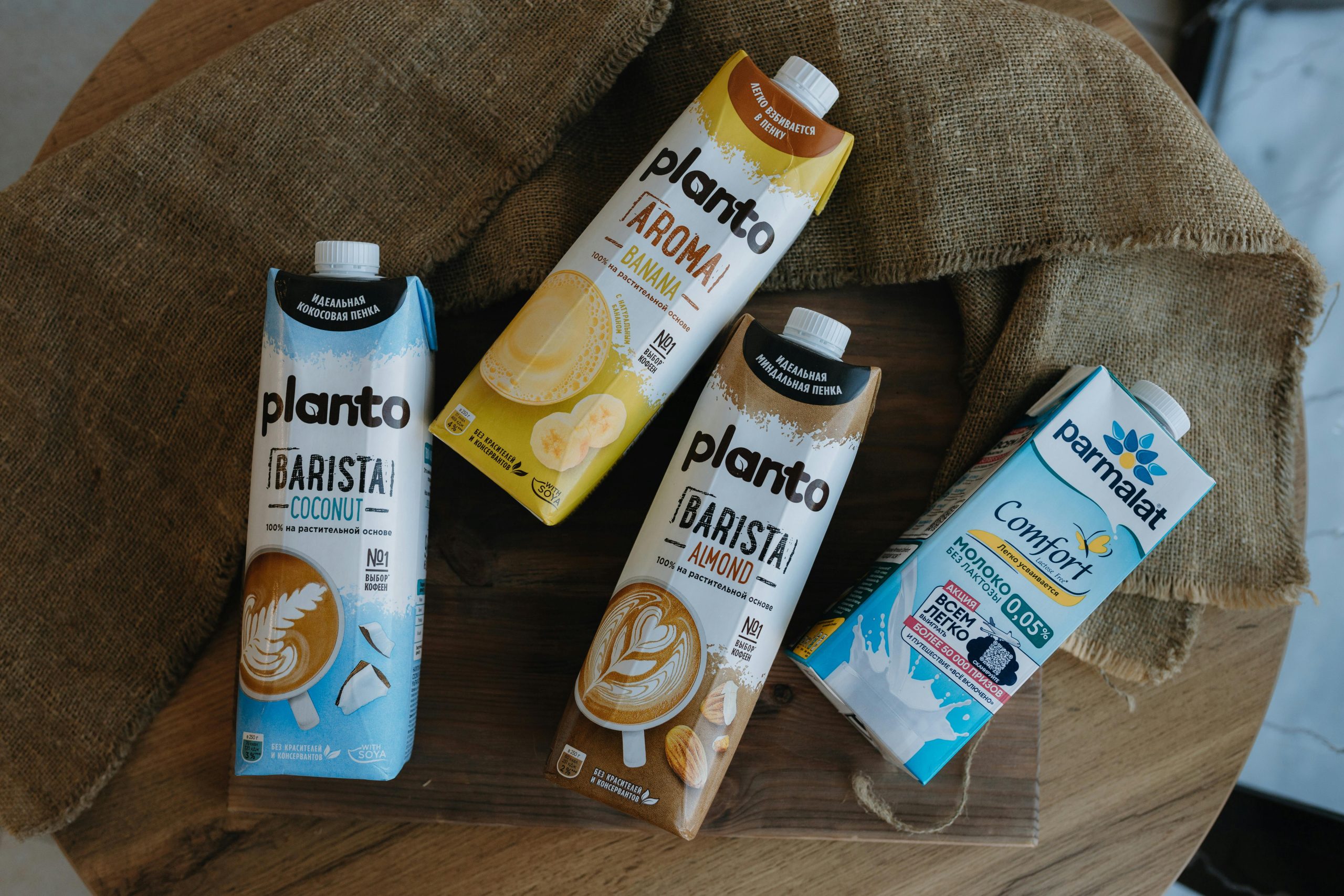 Top view of plant-based and dairy milk cartons on a rustic wooden table.