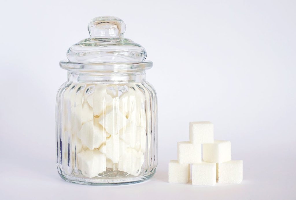 Crafting Captivating Headlines: Your awesome post title goes here A clear glass jar filled with sugar cubes next to stacked cubes on a white background.